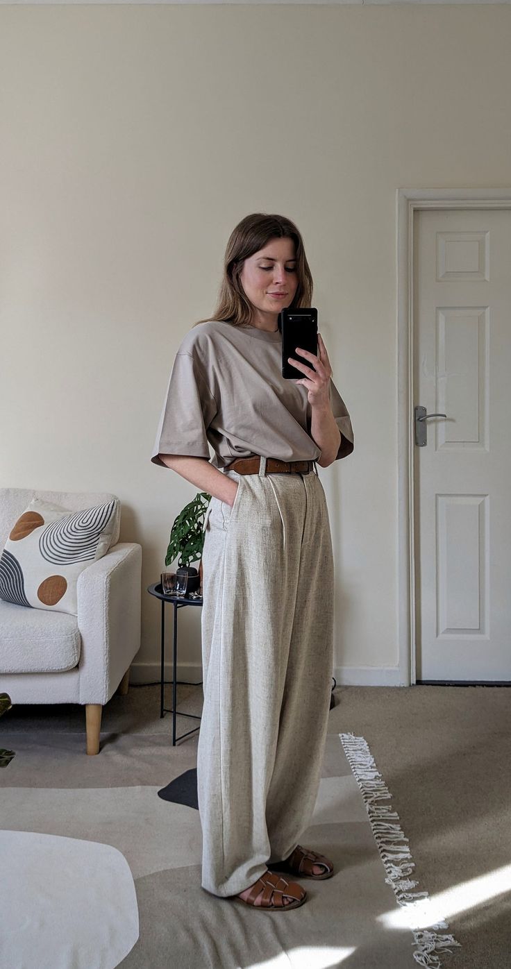 A woman stands in front of a mirror. She wears a light stone-coloured t-shirt, off-white trousers, a brown belt and brown leather fisherman sandals. Summer Elevated Casual, Oversized Outfit Summer, Casual Oversized Outfits, Linen Shirts Women Outfits, Fisherman Sandals Outfit, Linen Trousers Outfit, Linen Shirt Outfit, Comfy Jeans Outfit, Oversize Tshirt Outfits