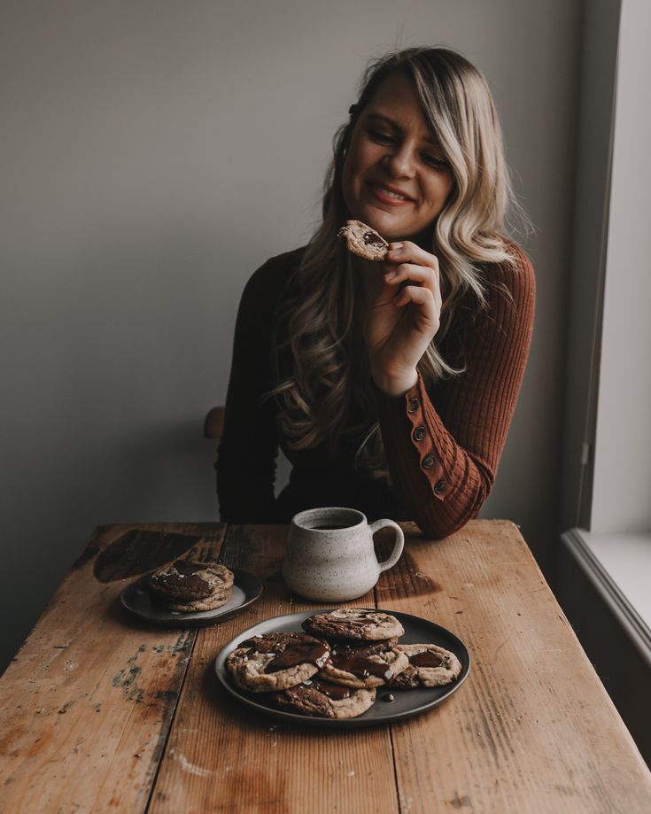 a woman sitting at a table eating cookies