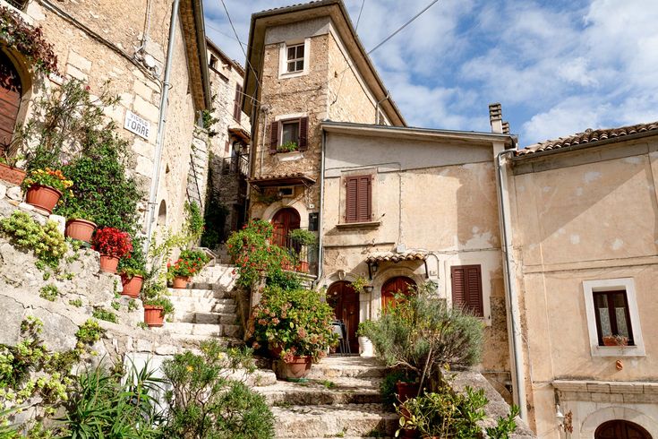 an old stone building with potted plants on the steps and flowers growing up to it