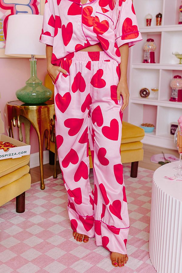 - Get your beauty sleep in these sweet pajama pants! - Unlined material with a pink heart print and accent piping - An elastic waistline - Functional side pockets - A relaxed silhouette that ends in straight hemline Pink Sleepwear With Pockets For Loungewear, Pink Heart Print Sleepwear For Pajama Party, Pink Wide Leg Lounging Pants, Pink Lounging Bottoms With Pockets, Pink Sleepwear For Valentine's Day, Spring Sleep Bottoms In Pink, Pink Valentine's Day Sleepwear, Pink Wide Leg Sleepwear For Loungewear, Pink Heart Print Bottoms For Spring