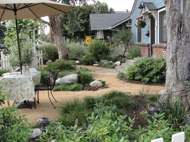 an outdoor patio with tables and chairs in the middle, surrounded by plants and trees