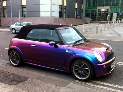 a purple and blue convertible car parked on the side of the road