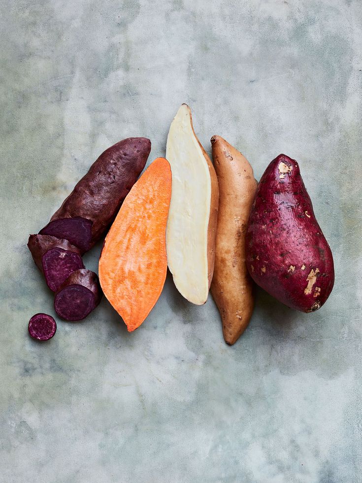 four different types of vegetables are arranged on a gray surface, including beets, carrots and potatoes