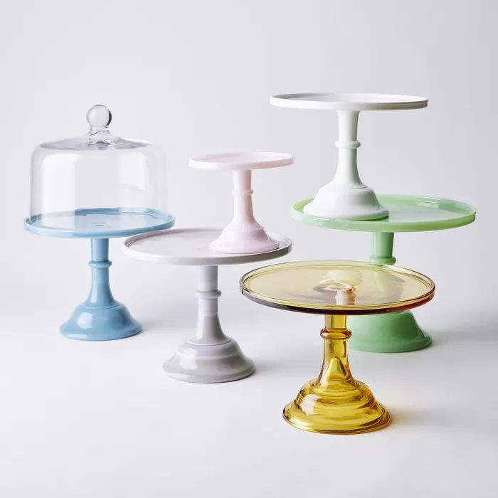 three different colored cake stands on a white surface