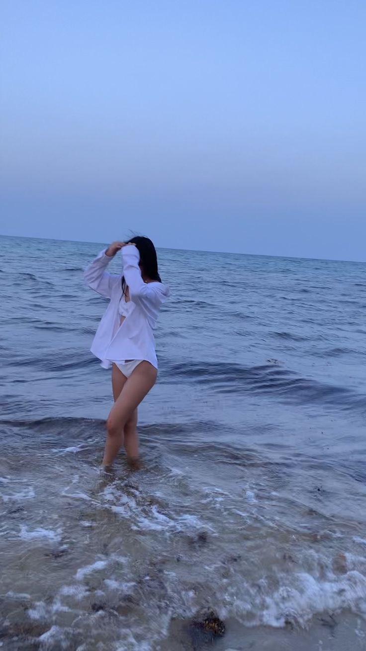 a woman is standing in the water at the beach