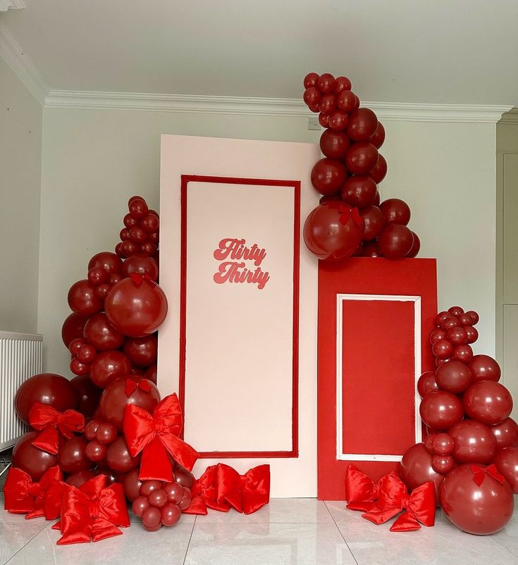 red balloons and streamers are on the floor next to a large card with a happy birthday message