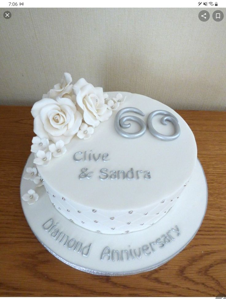 a white wedding cake with flowers and the number sixty on it's side, sitting on a wooden table