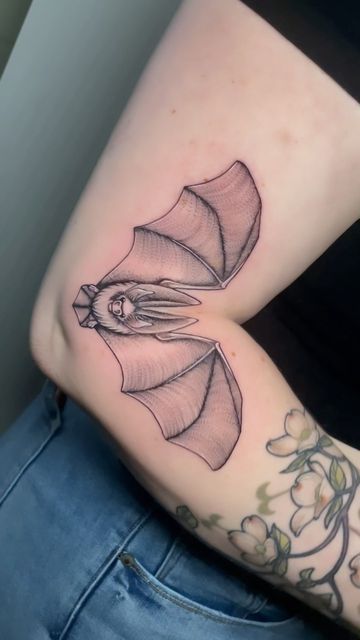 a woman's arm with a bat tattoo on it