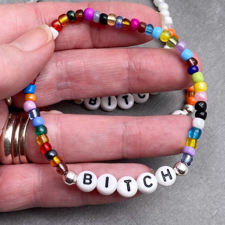 This funny BITCH glass seed bead bracelet is the perfect little joke gift for you bestie, to show how much you appreciate them! This custom made Bitch bracelet has 4mm glass seed beads, silver tone metal spacer beads and flat white acrylic letter beads, which are 7mm diameter. It is thread on strong elastic and will stretch a little bit so you can roll it onto your wrist gently. Allergy friendly, lightweight and super comfortable to wear! Comes in 9 gorgeous colour mix options and 12 sizes up to Novelty Colorful Beaded Bracelets As Gifts, Novelty White Stretch Bracelet With Round Beads, White Novelty Stretch Bracelet With Round Beads, Trendy Nickel-free Beaded Bracelets With Round Beads, Trendy Nickel-free Round Beaded Bracelets, Novelty Personalized Beaded Bracelets With Round Beads, Novelty Letter Beads Jewelry As Gift, Novelty White Beaded Bracelets For Friendship, Handmade White Beaded Novelty Bracelets