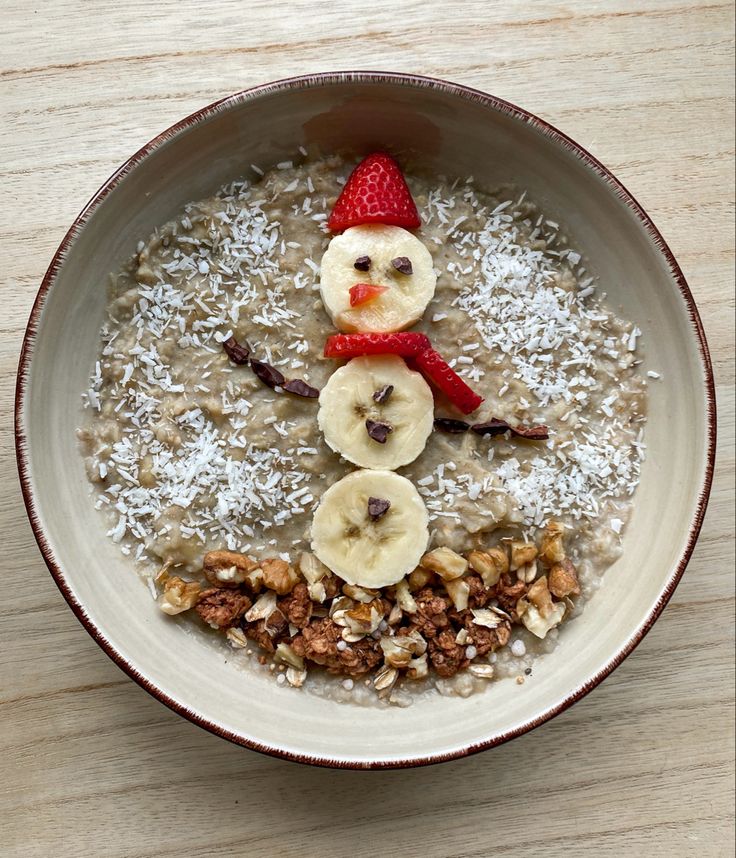 a bowl filled with oatmeal topped with bananas, nuts and a snowman