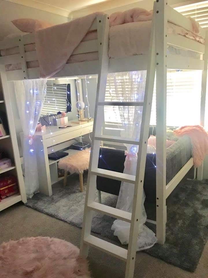 a white bunk bed sitting in a bedroom next to a desk and window with curtains on it