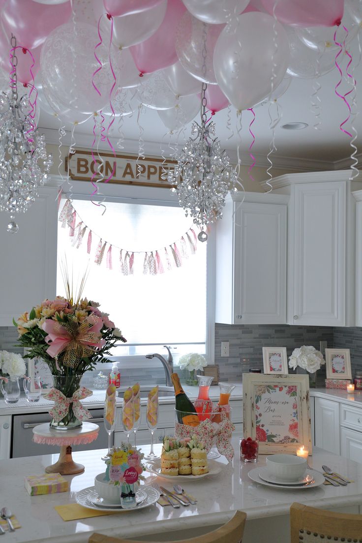 balloons are hanging from the ceiling above a kitchen counter with plates and cups on it