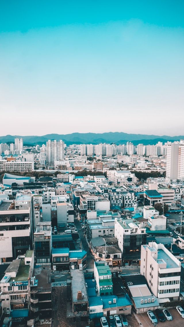 an aerial view of a city with lots of tall buildings in the foreground and mountains in the background