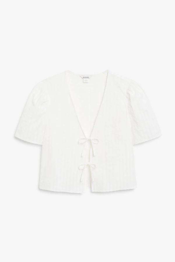 a white cropped cardigan top with an open front and tie at the waist