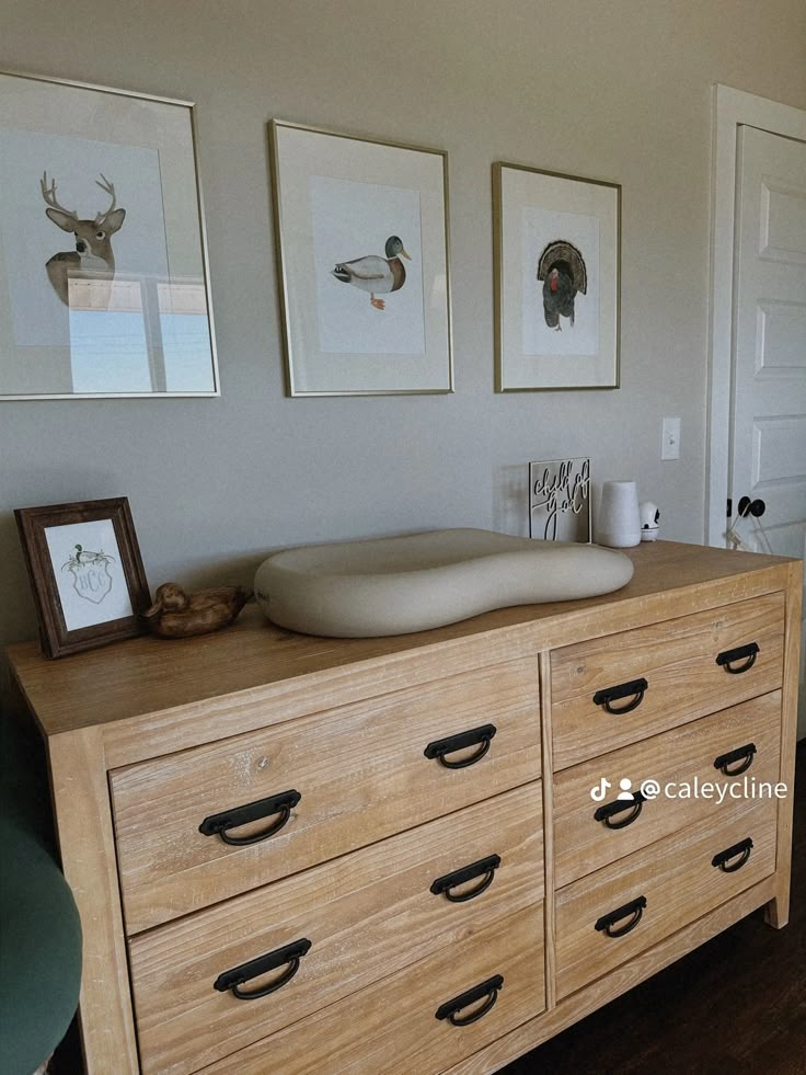 a dresser with drawers and pictures on the wall