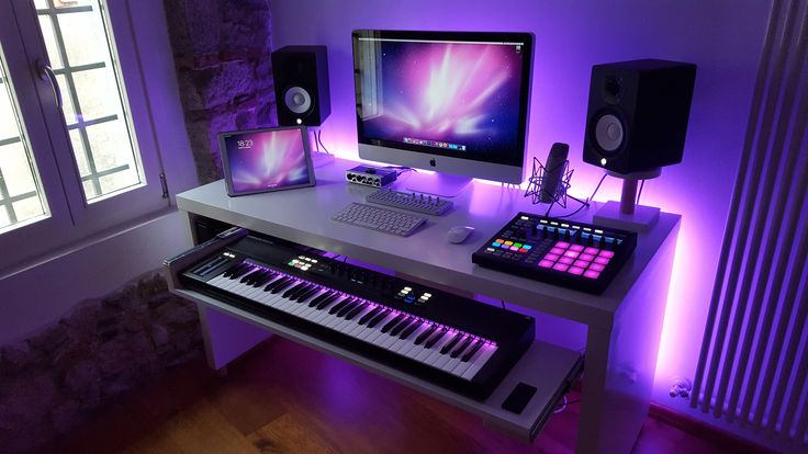 a computer desk with two monitors, keyboard and sound board on it in front of a window