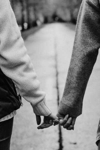 two people holding hands while walking down the street