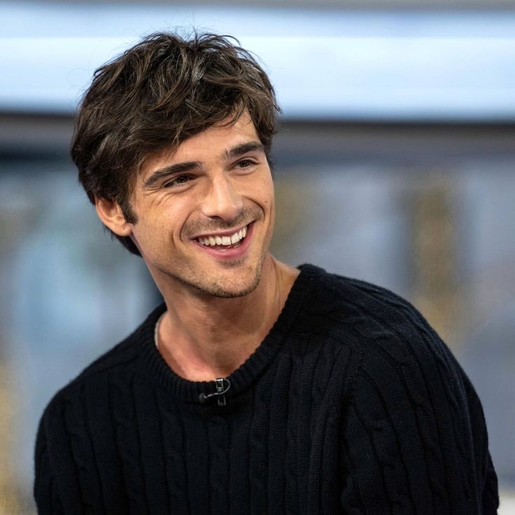 a young man smiling and wearing a black sweater