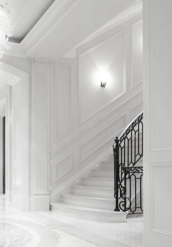 an elegant staircase with wrought iron handrails and chandelier in a white room