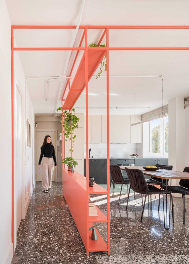 a woman is walking down the hallway in an open concept home with orange and pink accents