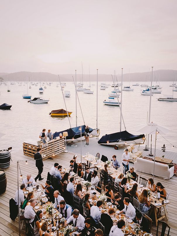 a group of people sitting at tables in front of boats