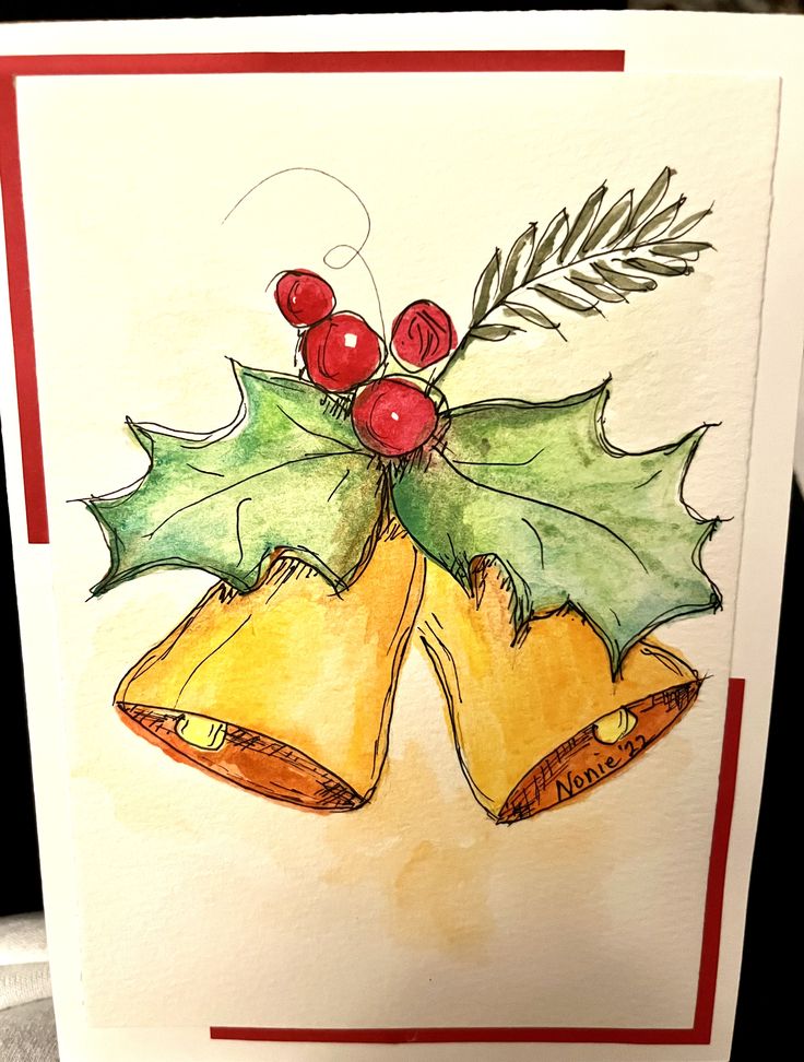 a card with two bells and holly leaves on it, sitting on top of a table