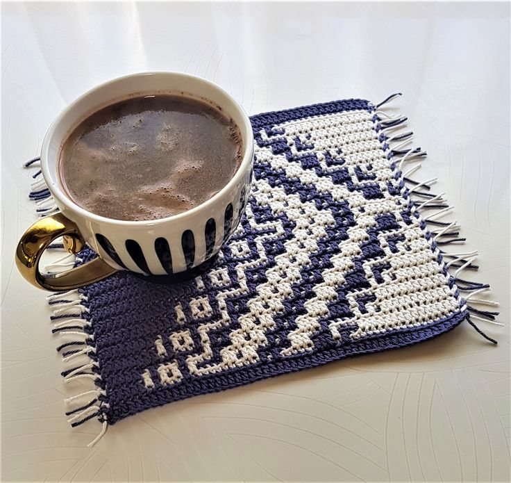 a cup of hot chocolate sitting on top of a blue and white place mat next to a book