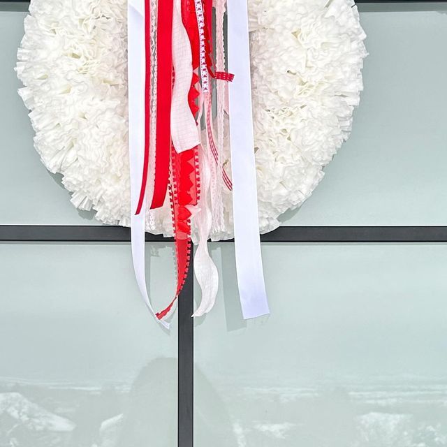 a white wreath with red, white and blue ribbons hanging from it's side