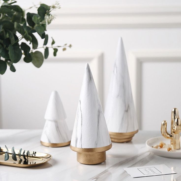 three white napkins with gold trim are sitting on a table next to a potted plant