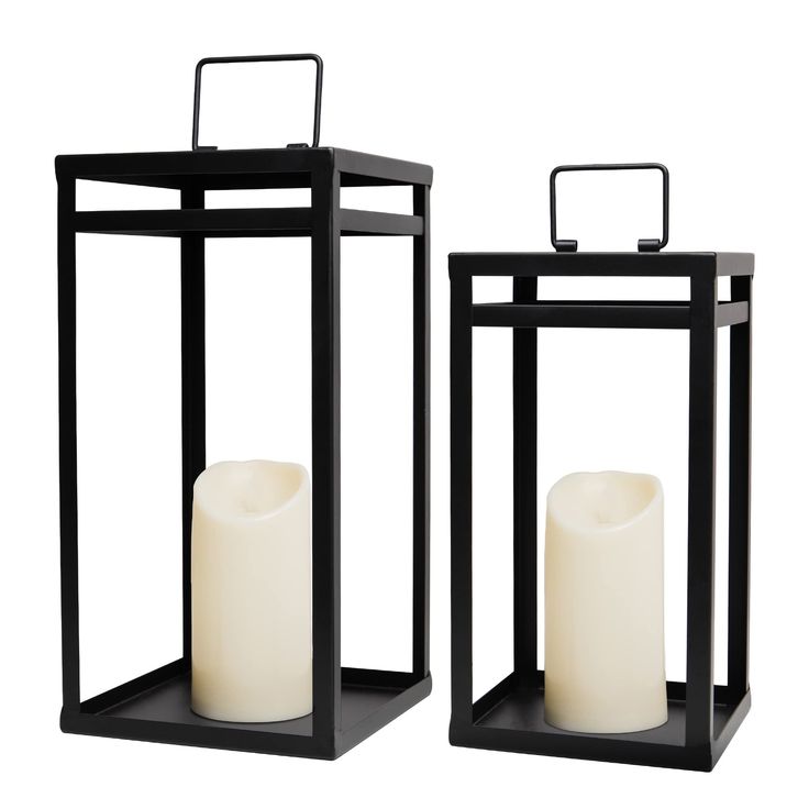 two black candle holders with white candles in them