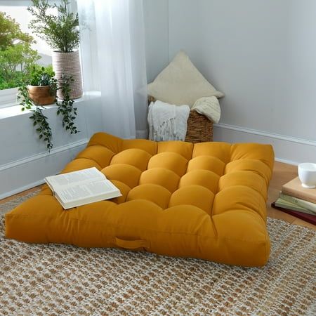 an orange futon mattress sitting on top of a rug next to a potted plant