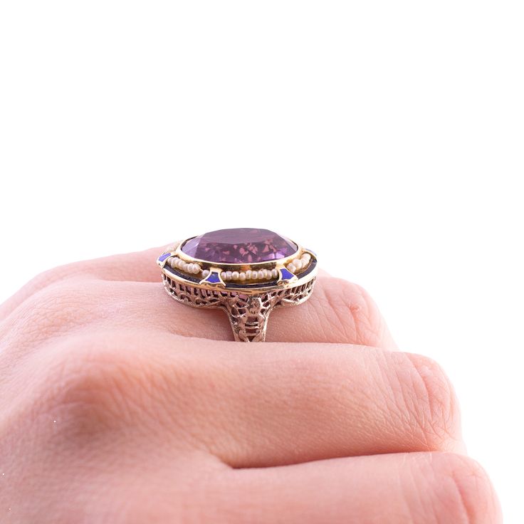 An Art Deco Cocktail Ring Amethyst and Seed Pearls 14K yellow and white gold From the 1920's The ring fits close to a size 6, pulls up about 5.25 on the ring sizer but the back is open behind the amethyst Wear consistent with the age of the piece, some enamel is chipped but otherwise in good condition 6.5 grams Antique 14k Gold Amethyst Ring, Art Deco Oval Amethyst Ring, Antique Amethyst Jewelry Stamped 14k, Art Deco 14k Gold Jewelry With Center Stone, Heirloom Style Oval Enamel Ring For Formal Occasions, Art Deco 14k Gold Rings With Center Stone, Oval Heirloom Enamel Ring For Formal Occasions, Collectible Oval Amethyst Ring In 14k Gold, Art Deco 14k Gold Ring With Center Stone