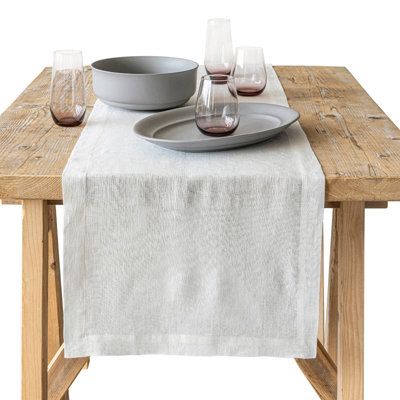 a wooden table topped with a plate and wine glasses next to a bowl on top of it