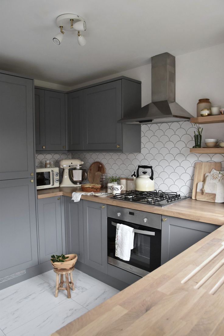 a kitchen with gray cabinets and wooden counter tops, along with a stove top oven