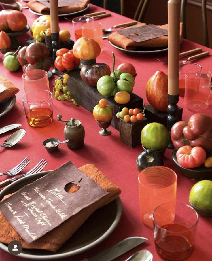 the table is set with many different types of fruit and silverware, including apples