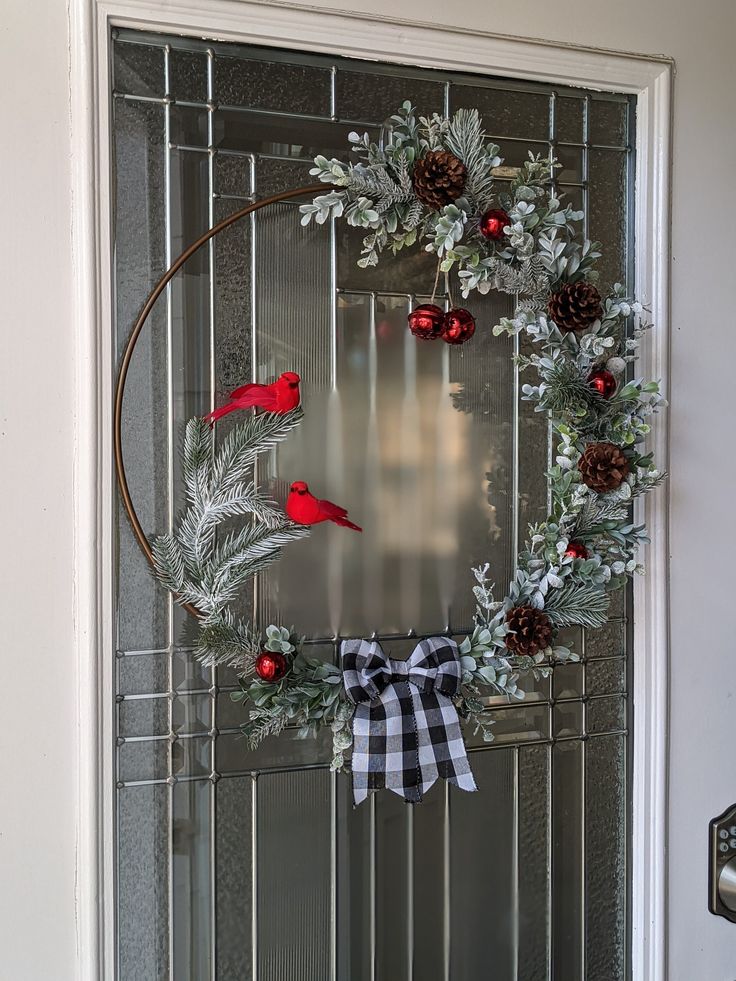 a wreath with red birds and pine cones hanging on the front door to welcome guests