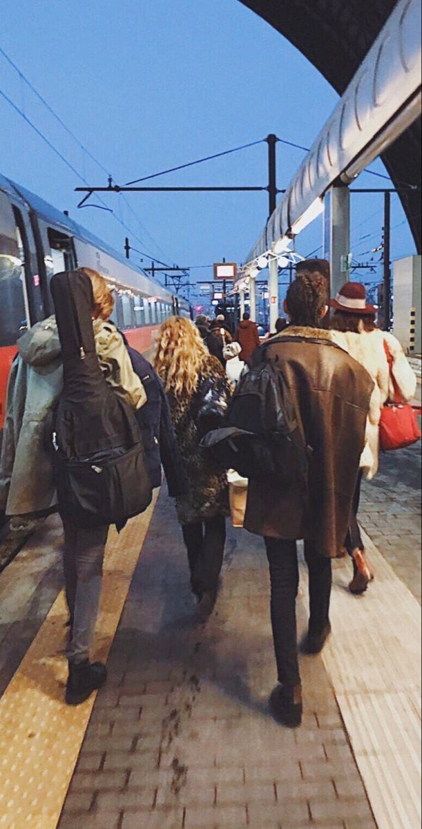 several people are walking towards a train at the station