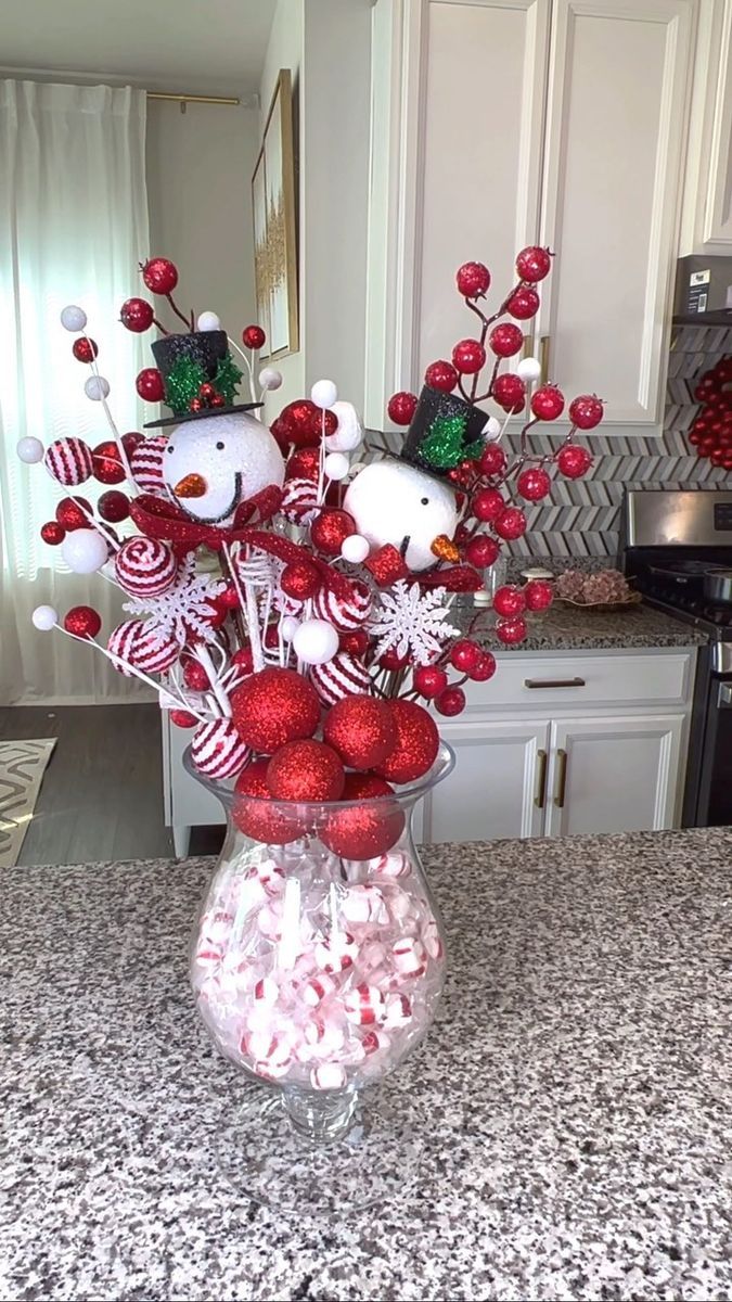 a glass vase filled with candy canes and snowmen on top of a counter