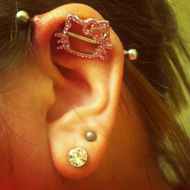 a woman wearing an ear piercing with pink crystals