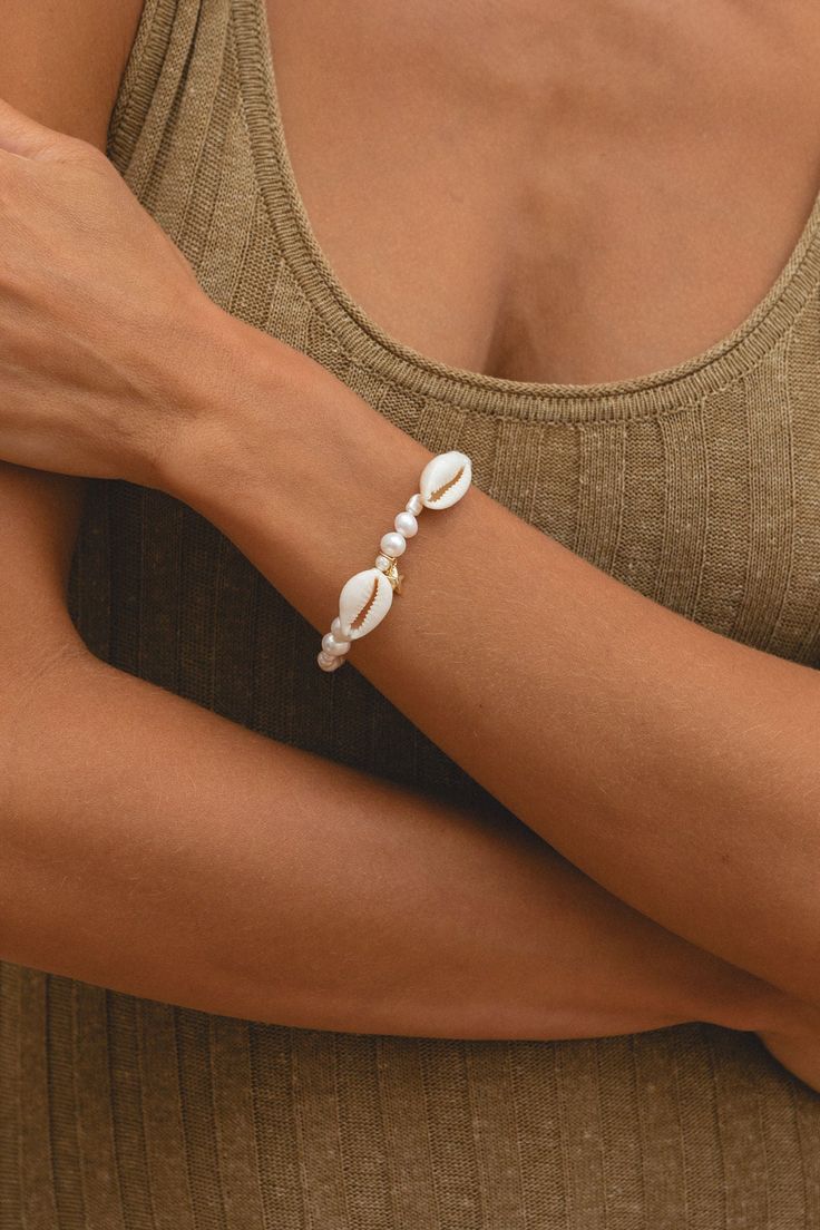 Shine bright like the sun with our Sun-Kissed Bracelet! Featuring a pearl cowrie shell and a dainty starfish charm, this accessory will add a touch of beachy vibes to any outfit. Whether you're lounging in the sun or hitting the town. Length: 6-7.5" Crafted with 14K Gold Filled Chain Handmade with love from San Clemente, CA. Part of the Taylor Hayden Collection. Vacation Shell-shaped Jewelry With Pearl Charm, Bohemian Pearl Charm Jewelry For Vacation, Ocean-inspired Summer Jewelry With Pearl Charm, Summer Ocean-inspired Jewelry With Pearl Charm, Casual Shell Bracelets For Beach Season, Bohemian Vacation Jewelry With Pearl Charm, Shell Jewelry With Pearl Charm For Vacation, Vacation Shell Jewelry With Pearl Charm, Summer Vacation Jewelry With Pearl Charm