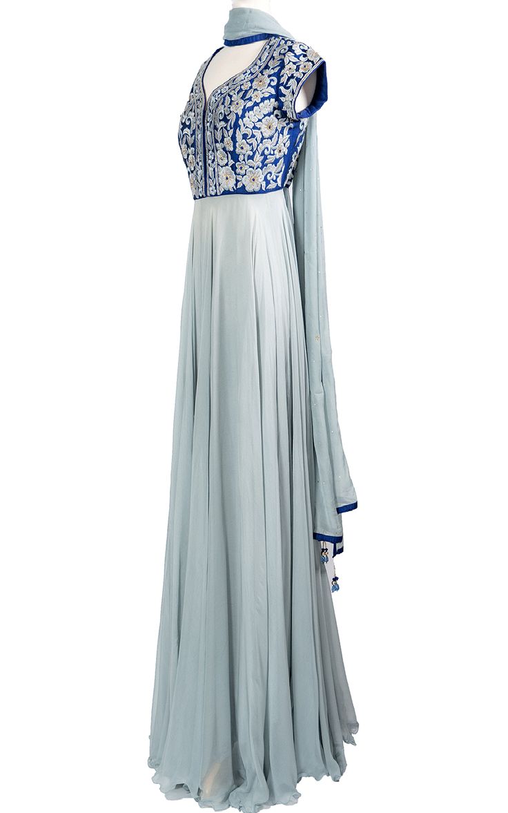 An elegant cool blue chiffon Anarkali drapes beautifully across the body and stands out with a raw silk royal blue top with tonal thread and zari embroidery.Length: 63Fabric: Top - Raw Silk, Gown / Dupatta - ChiffonEmbroidery: Thread, Stone Silk Blue Anarkali Set For Navratri, Elegant Blue Anarkali Set With Cutdana, Blue Georgette Anarkali Set With Cutdana, Blue Raw Silk Churidar For Navratri, Silk Churidar With Traditional Drape For Reception, Blue Silk Churidar For Navratri, Blue Georgette Anarkali Set With Traditional Drape, Blue Floor-length Traditional Wear For Transitional Season, Blue Transitional Traditional Floor-length Wear