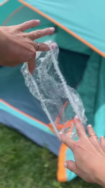 two hands reaching out to grab something from a bag in front of an open tent