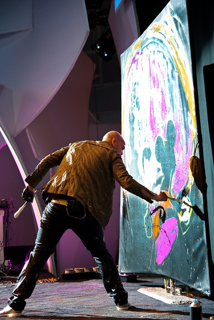 a man is standing in front of an art piece with paint splattered on it