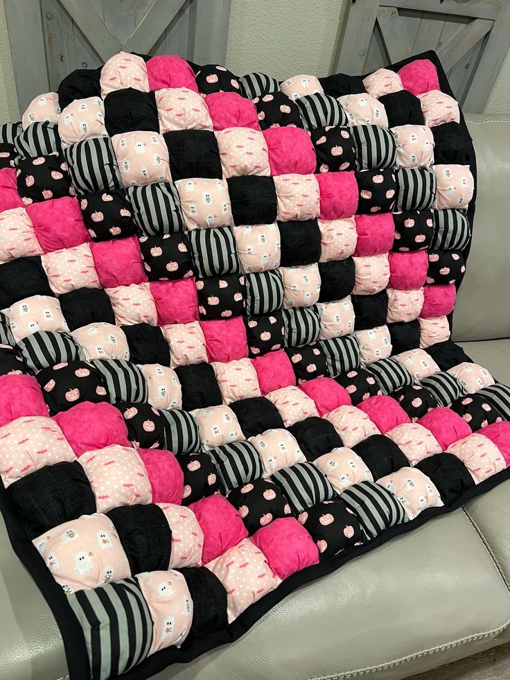 a black and pink patchwork quilt sitting on top of a couch