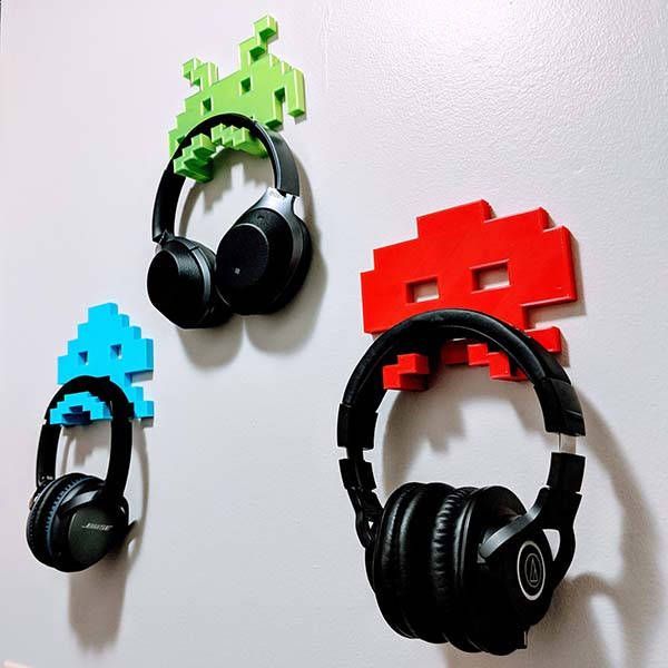 two headphones are hanging on the wall next to each other with different colored headsets