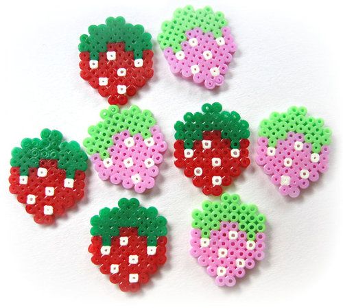 six perler bead strawberrys on a white surface with green, red and pink beads