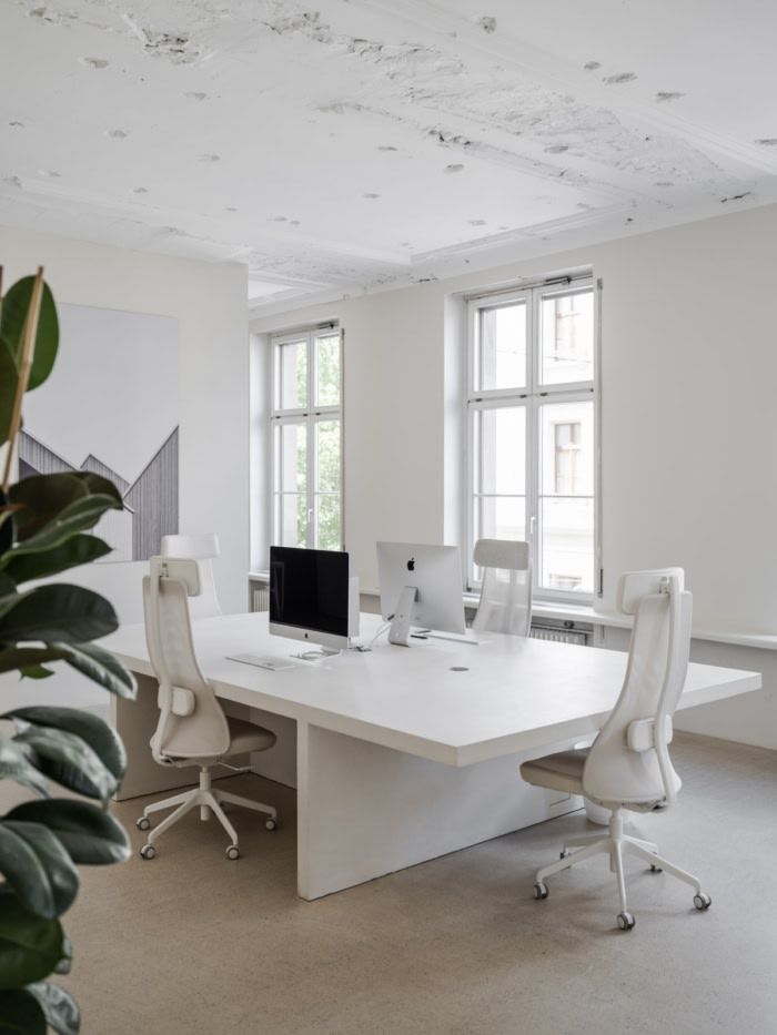 an office with white furniture and large windows