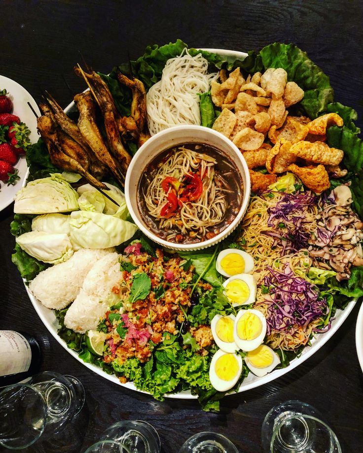 an assortment of food is displayed on a platter with wine glasses and plates around it