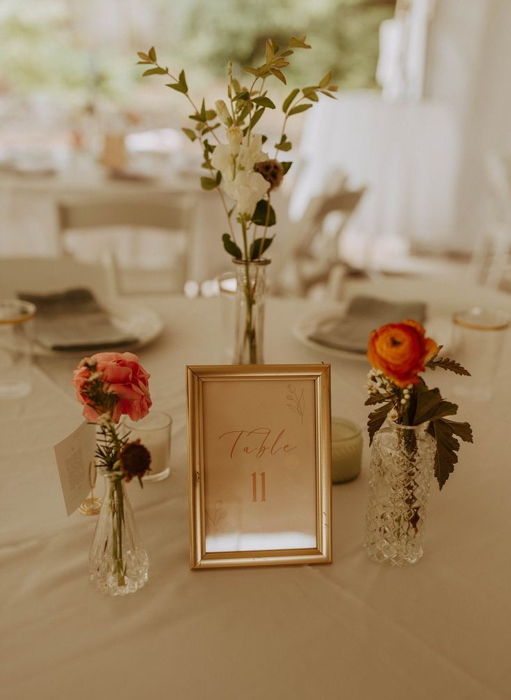 the table is set with vases and flowers