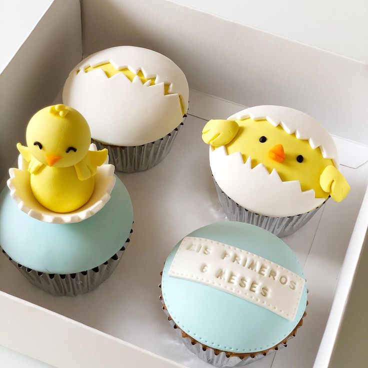 three decorated cupcakes in a box with rubber ducks